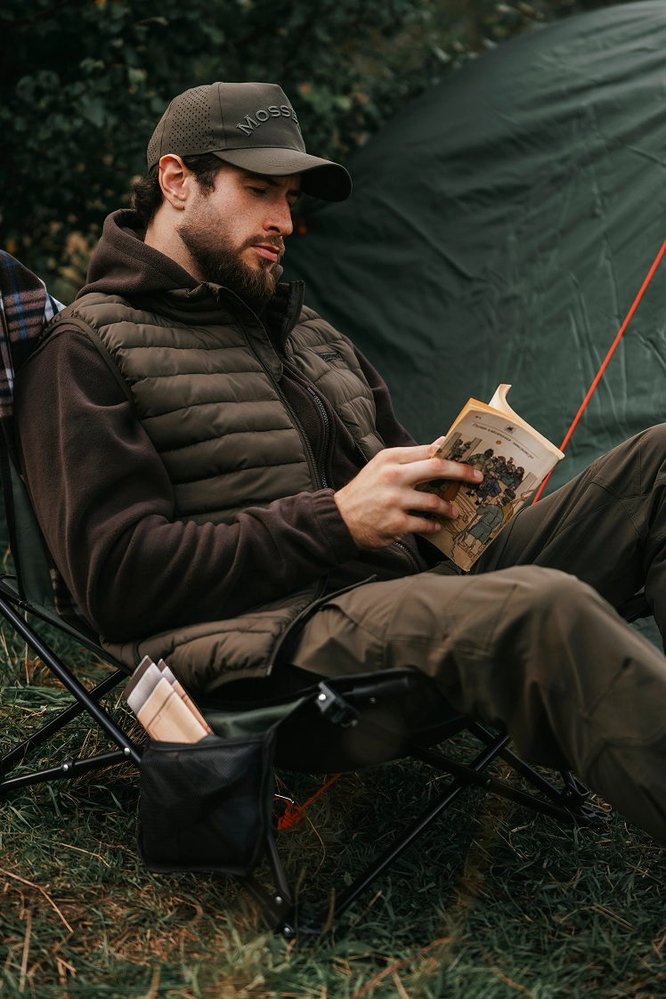 Рыбак читает книгу у палатки.