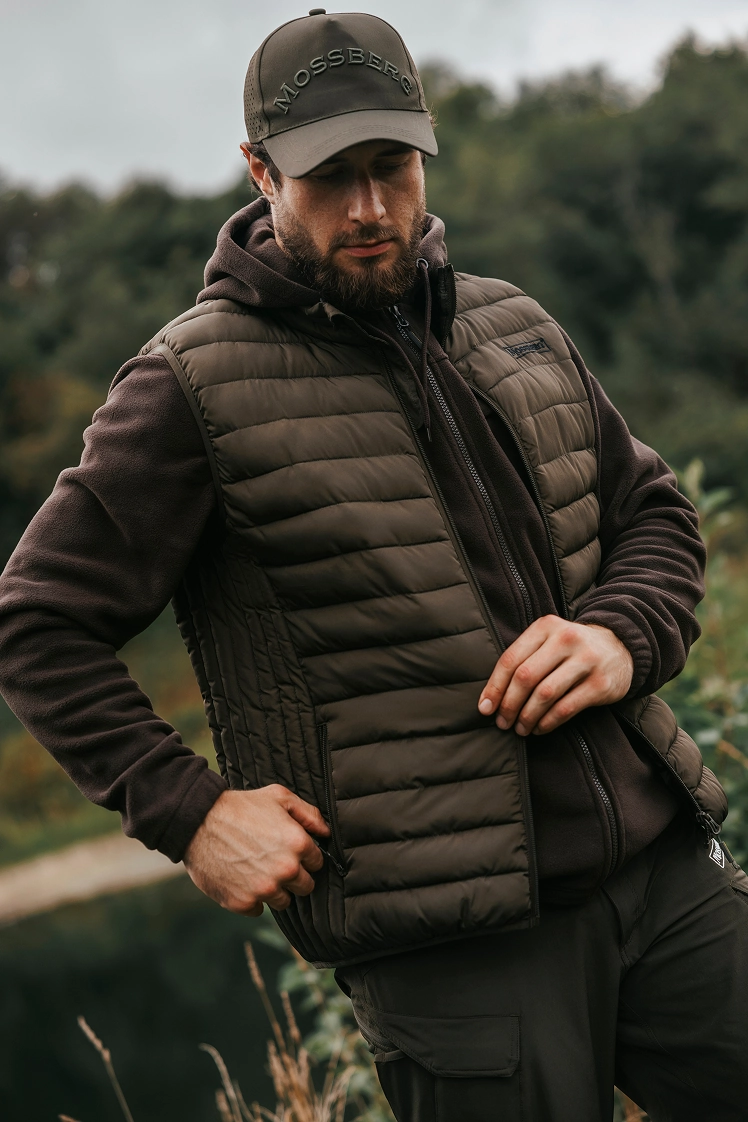 Рыбак застегивает карман водонепроницаемой жилетки Mossberg.