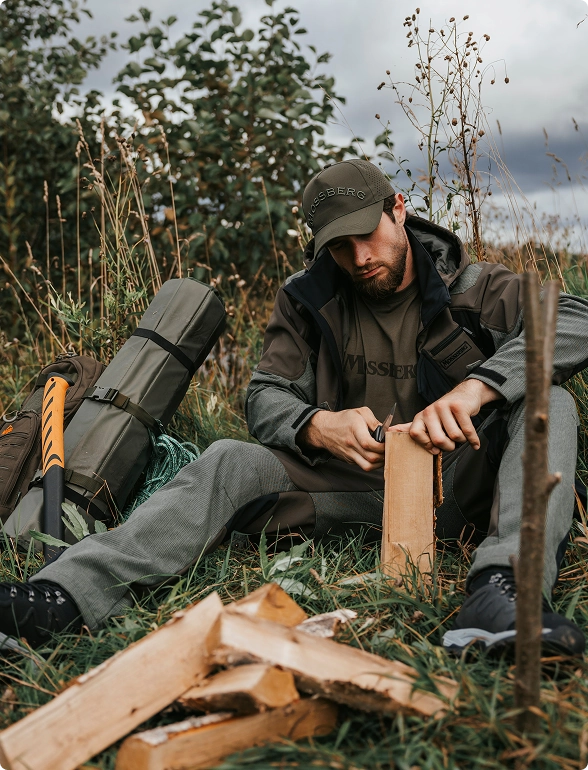 Охотник заготавливает дрова для костра.